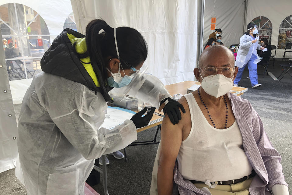 Victor Villegas, 78, right, receives a COVID-19 vaccine shot from a health care worker at a vaccination site in the Mission district of San Francisco, Monday, Feb. 8, 2021. Counties in California and other places in the U.S. are trying to ensure they vaccinate people in largely Black, Latino and working-class communities that have borne the brunt of the coronavirus pandemic. San Francisco is reserving some vaccines for seniors in the two ZIP codes hit hardest by the pandemic. (AP Photo/Haven Daley)