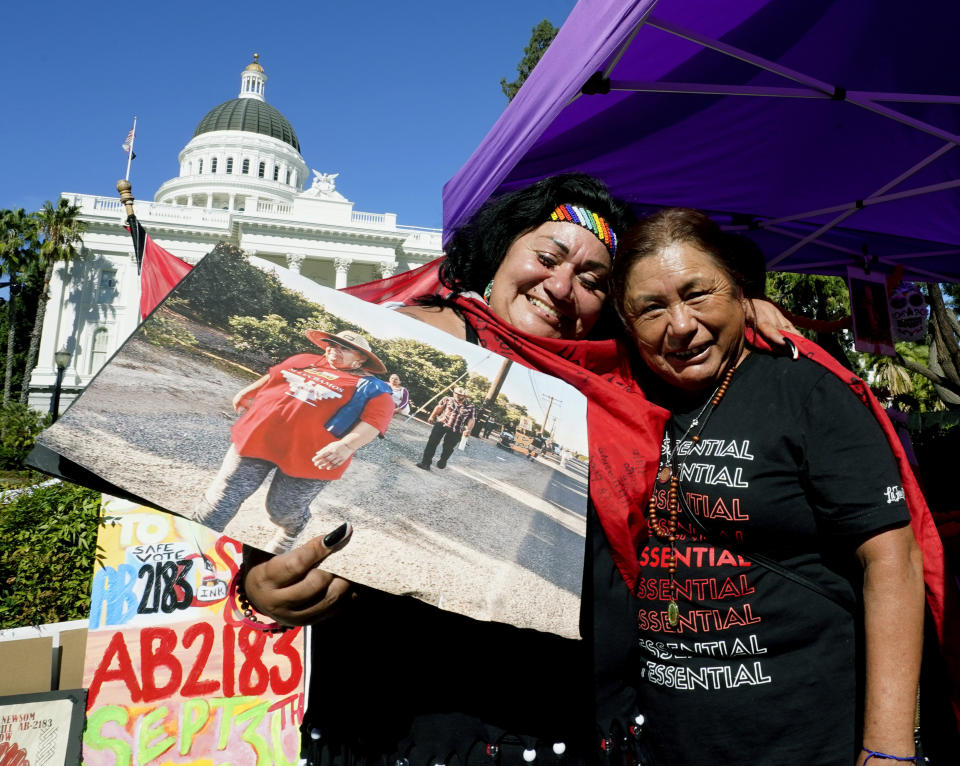 Farmworkers Cynthia Burgos, left and Teresa Maldonado, right, hug after Gov. Gavin Newsom signed a bill aimed at making it easier for farmworkers to unionize in Sacramento, Calif., Wednesday, Sept. 28, 2022. Newsom joined about two dozen farmworkers outside the state Capitol to sign the bill. Both Burgos and Maldonado had joined others in a march from Delano to Sacramento to draw attention to the bill. (AP Photo/Rich Pedroncelli)