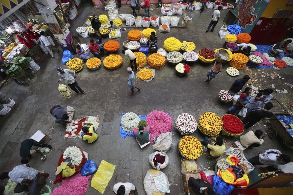 Flower vendors wait for buyers at a wholesale market in Bengaluru, India, Thursday, Sept. 24, 2020. The nation of 1.3 billion people is expected to become the COVID-19 pandemic's worst-hit country within weeks, surpassing the United States. (AP Photo/Aijaz Rahi)