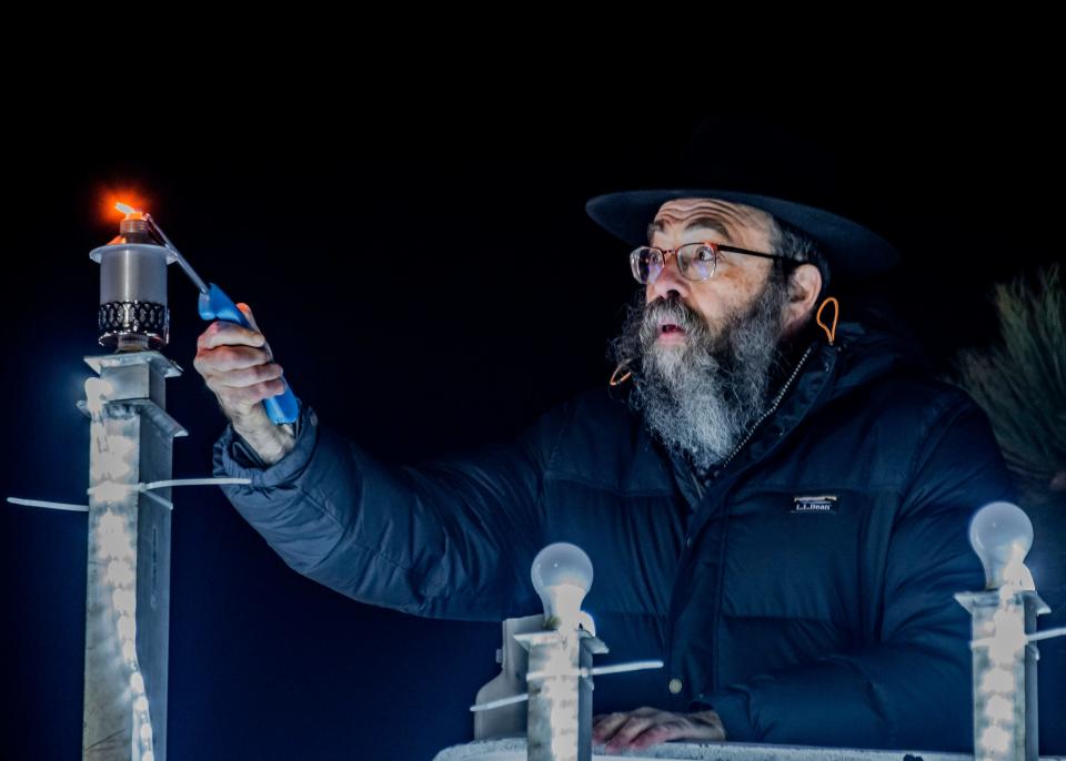 Rabbi Yitzchak Raskin of Chabad of Vermont  lights the topmost lamp on a menorah to celebrate the first night of Chanukah on the campus green at the University of Vermont in Burlington on Nov. 28, 2021.