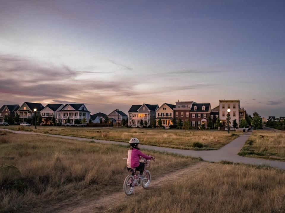 little girl in pink shirt and helmet rides her bike down a road in Denver, Colorado