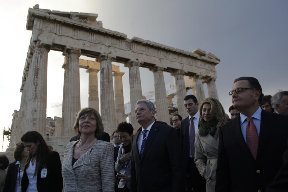 German President Joachim Gauck, center, and his partner Daniela Schadt are escorted by Greek Culture Minister Panos Panayotopoulos, right, on a visit to the ancient Acropolis in Athens, on Wednesday, March 5, 2014. Gauck is on a visit that will seek to lay to rest some of the ghosts of a brutal Nazi occupation, amid renewed anti-German sentiment stoked by Greece's financial crisis. His three-day visit will include a speech Friday at a site where German army troops massacred 92 villagers near the northeastern town of Ioannina, and a meeting with the town's Jewish community. (AP Photo/Kostas Tsironis)