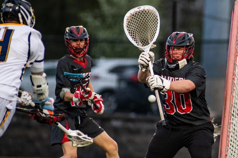 Red Hook goalkeeper Jack Melious, right, makes a save against Our Lady of Lourdes during a boys lacrosse game on April 19, 2024.