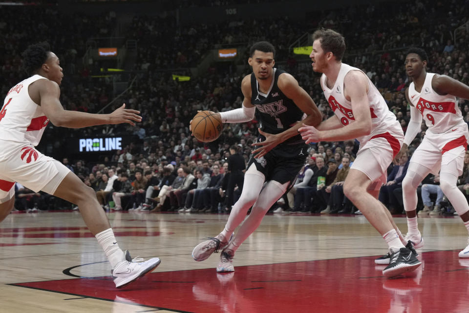 San Antonio Spurs center Victor Wembanyama (1) drives toward the basket as Toronto Raptors' Jakob Poeltl, second from right, defends during first-half NBA basketball game action in Toronto, Monday Feb. 12, 2024. (Chris Young/The Canadian Press via AP)