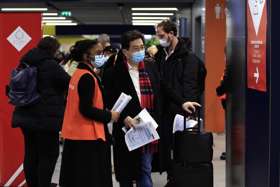 Passengers arriving from China wait in front of a COVID-19 testing area set at the Roissy Charles de Gaulle airport, north of Paris, Sunday, Jan. 1, 2023. France says it will require negative COVID-19 tests of all passengers arriving from China and is urging French citizens to avoid nonessential travel to China. (AP Photo/Aurelien Morissard)