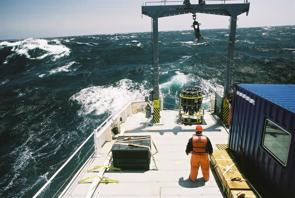 In stormy waters, scientists prepare to drop an ocean-collecting device into the water.