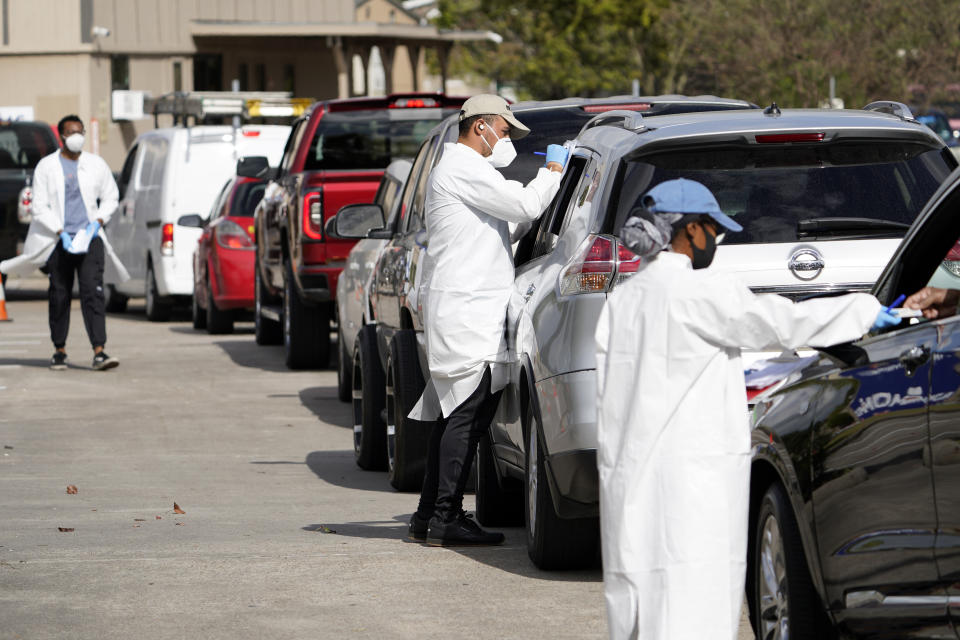 Healthcare workers process people waiting in line at a United Memorial Medical Center COVID-19 testing site Thursday, Nov. 19, 2020, in Houston. Texas is rushing thousands of additional medical staff to overworked hospitals as the number of hospitalized COVID-19 patients increases. (AP Photo/David J. Phillip)