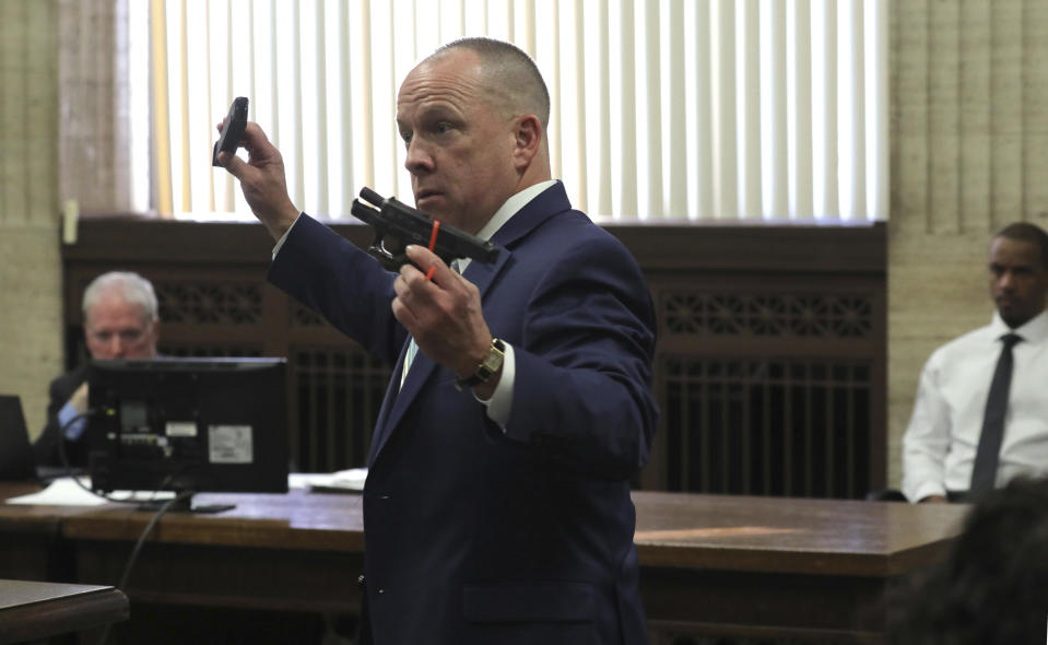 Prosecuting attorney John Maher displays the weapons during closing statements in Shomari Legghette's murder trial at the Leighton Criminal Courthouse, Friday, March 13, 2020, in Chicago. Legghette is on trial for first-degree murder in the Feb. 13, 2018, killing of Chicago Police Cmdr. Paul Bauer. (Antonio Perez/Chicago Tribune via AP)