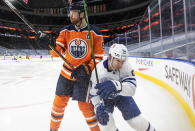 Edmonton Oilers' Adam Larsson (6) and Toronto Maple Leafs' Alex Barabanov (94) battle for the puck during first-period NHL hockey game action in Edmonton, Alberta, Monday, March 1, 2021. (Jason Franson/The Canadian Press via AP)