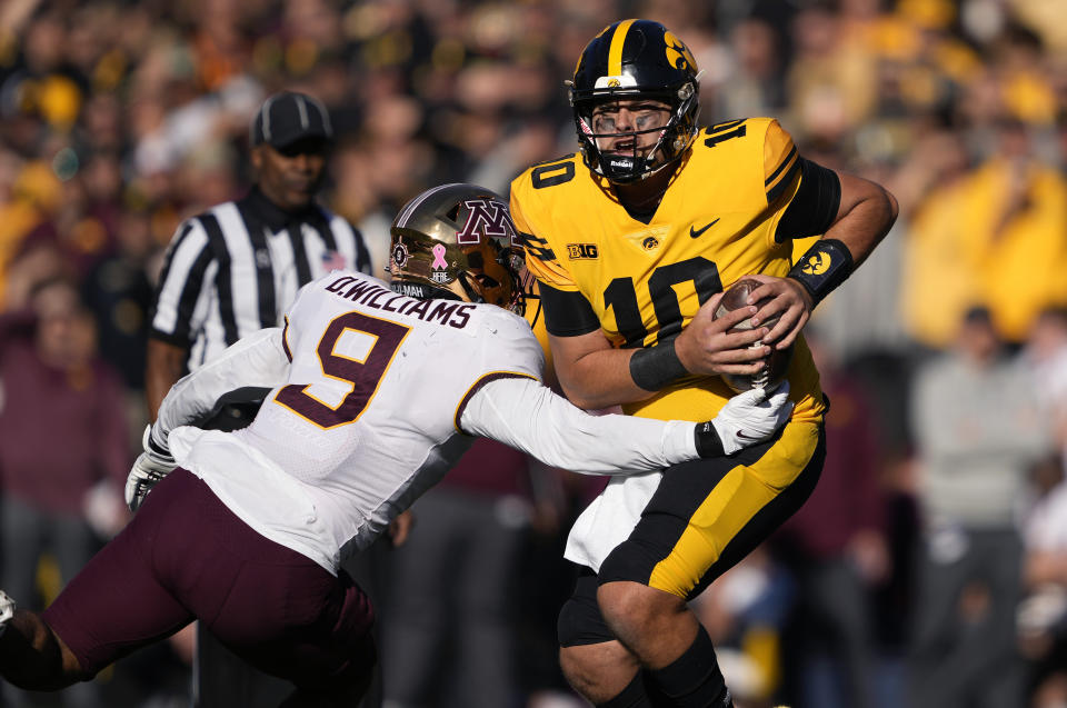 Iowa quarterback Deacon Hill (10) runs the ball as he eludes a tackle by Minnesota linebacker Devon Williams (9) during the first half of an NCAA college football game, Saturday, Oct. 21, 2023, in Iowa City, Iowa. (AP Photo/Matthew Putney)