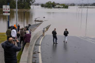 People look at the flooded Windsor Bridge at Windsor on the outskirts of Sydney, Australia, Tuesday, July 5, 2022. Hundreds of homes have been inundated in and around Australia’s largest city in a flood emergency that was impacting 50,000 people, officials said Tuesday.(AP Photo/Mark Baker)