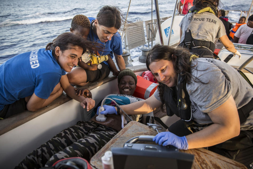 Doctors tend to a pregnant woman on a Mediterranea Saving Humans NGO boat, as they sail off Italy's southernmost island of Lampedusa, just outside Italian territorial waters, on Thursday, July 4, 2019. An Italian humanitarian group whose boat has been barred from docking in Lampedusa said the health of the 54 migrants it rescued at sea is rapidly deteriorating, prompting fears of another standoff with Italy's populist government. Mediterranea Saving Humans said Friday in a tweet that its sailing boat ALEX was off Italy's southernmost island of Lampedusa, just outside Italian territorial waters, and that it has been banned from entering Italian jurisdiction by ministerial decree. (AP Photo/Olmo Calvo)