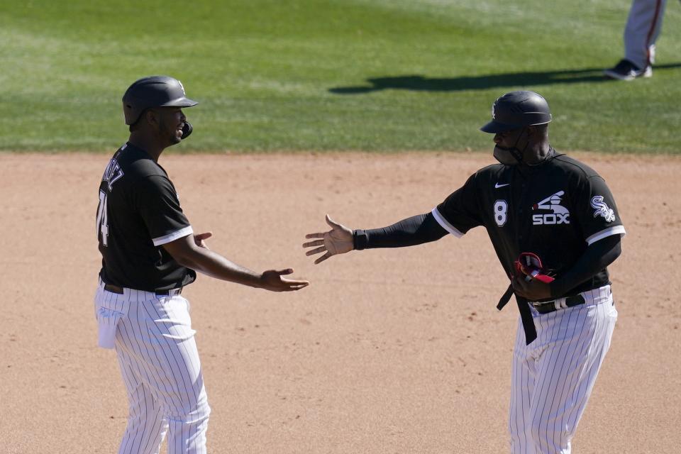 Chicago White Sox's Eloy Jimenez, left, is congratulated by first base coach Daryl Boston after Jimenez hit an RBI double against the San Francisco Giants during the fifth inning of a spring training baseball game Monday, March 22, 2021, in Phoenix. (AP Photo/Ross D. Franklin)