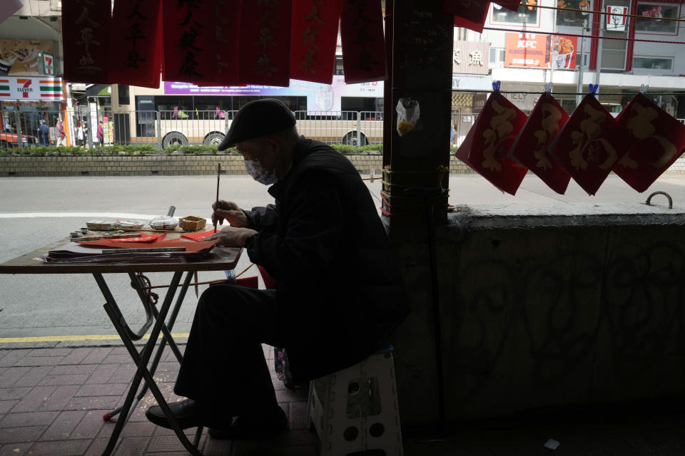 Chan King-fat, 80-year-old calligraphy artist writes "Fai Chun," traditional decorations with Chinese calligraphy in Hong Kong on Jan. 27, 2022. In the runup to the Lunar New Year, calligraphers set up on the streets of Hong Kong to write ink-brush phrases on traditional red paper banners for homes and offices. (AP Photo/Kin Cheung)