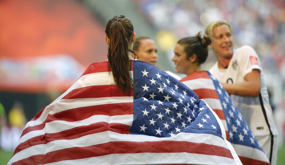 United States' Alex Morgan is draped in the U.S. flag as she celebrates with teammates after the U.S. beat Japan 5-2 in the FIFA Women's World Cup soccer championship in Vancouver, British Columbia, Canada, Sunday, July 5, 2015. (AP Photo/Elaine Thompson)