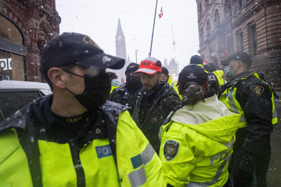 Police lead a protester towards a cruiser after making an arrest on Wellington Street, during an ongoing protest against COVID-19 measures that has grown into a broader anti-government protest, in Ottawa, Ontario, on Thursday, Feb. 17, 2022. (Justin Tang/The Canadian Press via AP)