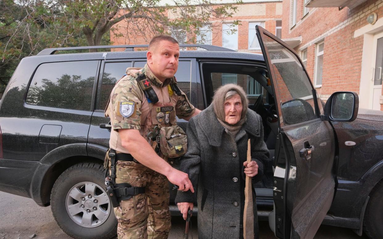 Ms Lomikovska is helped by a Ukrainian police officer after her six-mile journey with only a cane and a wooden stick for support