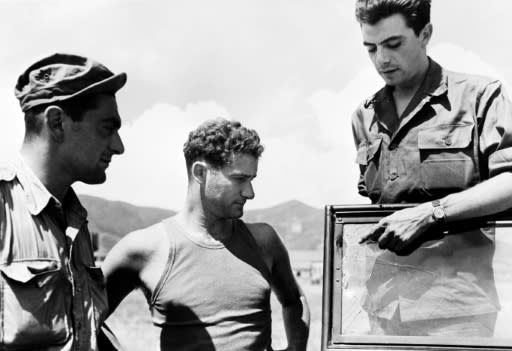 Journalists Alex Valentine (L) from Reuters, Jean-Marie de Premonville (C) and Henri de Turenne from the Agence France Presse point to bullet impacts on their jeep in 1950 during the Korean War