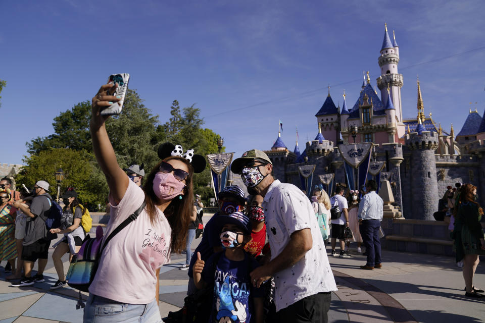 A family takes a photo in front of Sleeping Beauty's Castle at Disneyland in Anaheim, Calif., Friday, April 30, 2021. The iconic theme park in Southern California that was closed under the state's strict virus rules swung open its gates Friday and some visitors came in cheering and screaming with happiness. (AP Photo/Jae Hong)