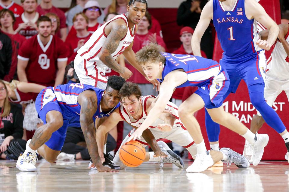 OU forward Sam Godwin (10) dives for the ball along with Kansas guard Johnny Furphy (10) and forward K.J. Adams Jr. (24) in the second half Saturday Lloyd Noble Center in Norman.
