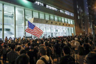 Protesters waving an American flag gather outside the Queen Elizabeth Stadium in Hong Kong, Thursday, Sept. 26, 2019. Scores of protesters chanted slogans outside a venue in downtown Hong Kong as embattled city leader Carrie Lam began a town hall session inside Thursday aimed at cooling down months of demonstrations for greater democracy in the semi-autonomous Chinese territory. (AP Photo/Vincent Thian)