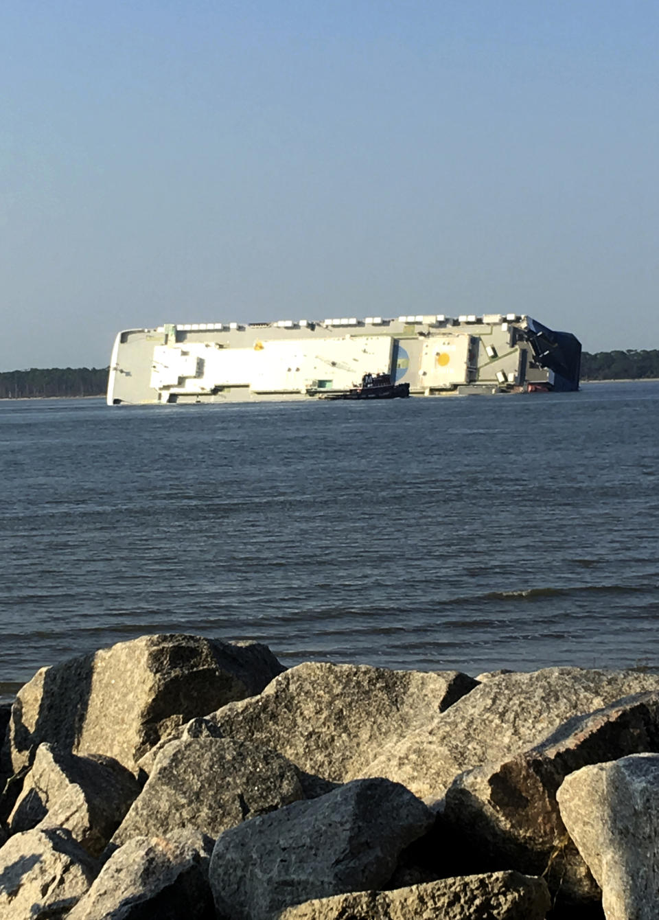 In this photo provided by Tara Jones, a capsized cargo ship is seen near a port on the Georgia coast, Sunday, Sept. 8, 2019. Rescuers were searching Sunday for multiple crew members of the ship that overturned and caught fire in St. Simons Sound, Ga. (Tara Jones via AP)