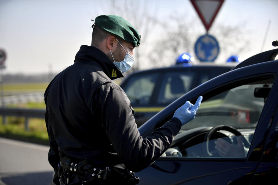 A tax police officer wearing a sanitary mask talks to a driver at a road block in Casalpusterlengo, Northern Italy, Monday, Feb. 24, 2020. Italy scrambled to check the spread of Europe's first major outbreak of the new viral disease amid rapidly rising numbers of infections. Road blocks were set up in at least some of 10 towns in Lombardy at the epicenter of the outbreak, to keep people from leaving or arriving. (Claudio Furlan/Lapresse via AP)