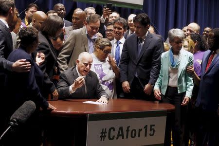 California Governor Jerry Brown (C) signs a bill hiking California's minimum wage to $15 by 2023 in Los Angeles, California, United States, April 4, 2016. REUTERS/Lucy Nicholson