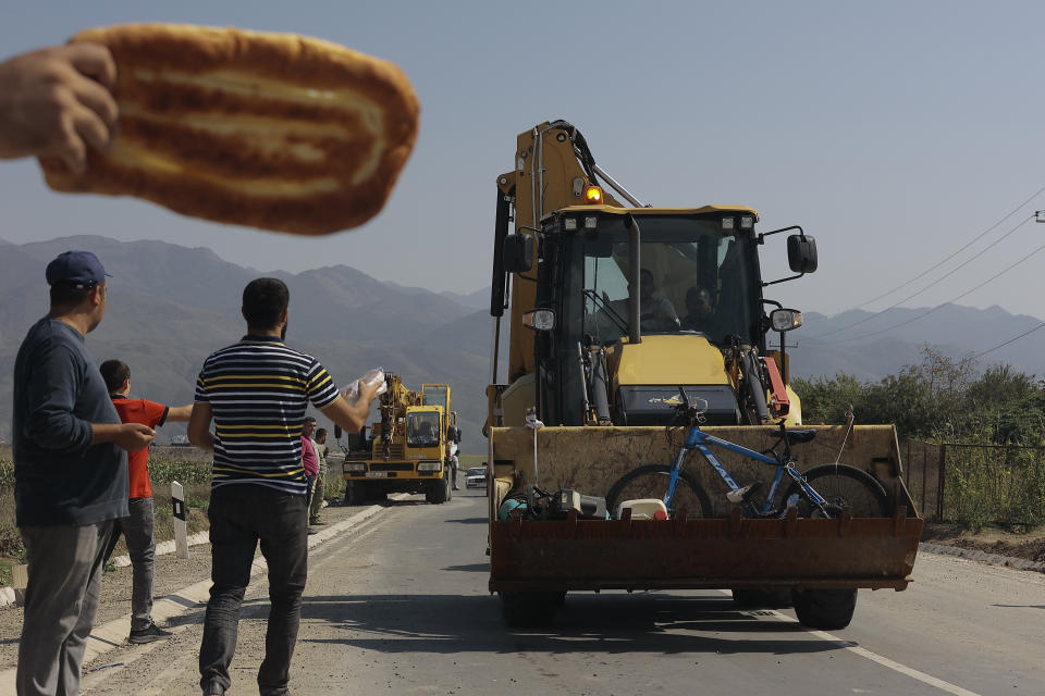 Volunteers offer food to ethnic Armenians fleeing from Nagorno-Karabakh on their way to Armenia's Kornidzor in Syunik region, Armenia, Friday, Sept. 29, 2023. More than 70% of Nagorno-Karabakh's original population has fled to Armenia as the region's separatist government said it will dissolve itself and the unrecognized republic inside Azerbaijan will cease to exist by year’s end after a three-decade bid for independence. (AP Photo/Vasily Krestyaninov)