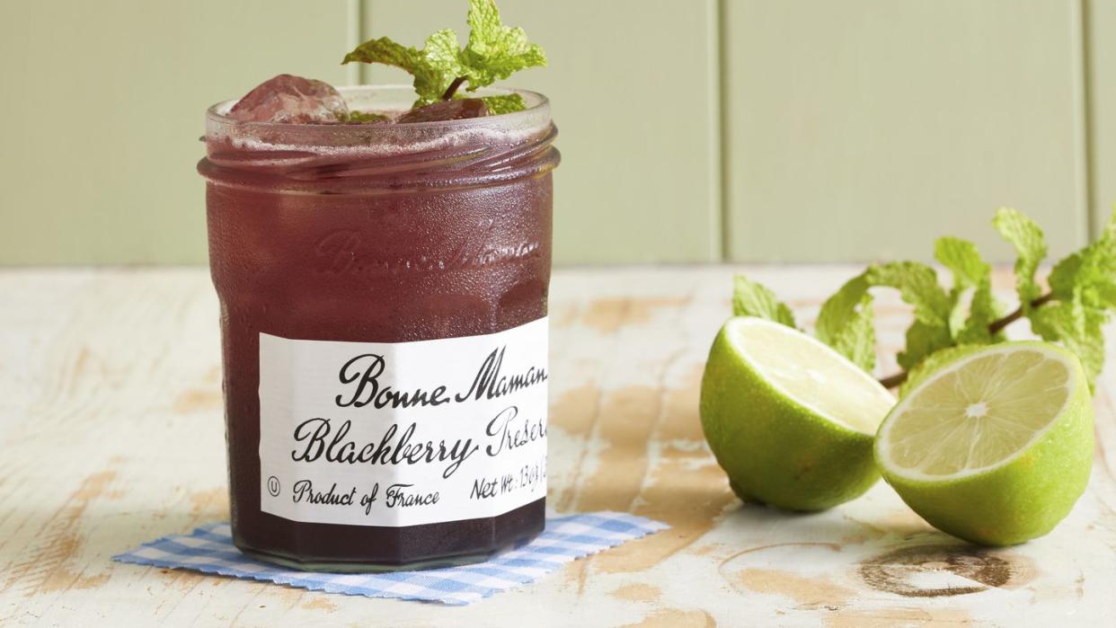 a blackberry jam jar with a drink in it and a sprig of mint on top