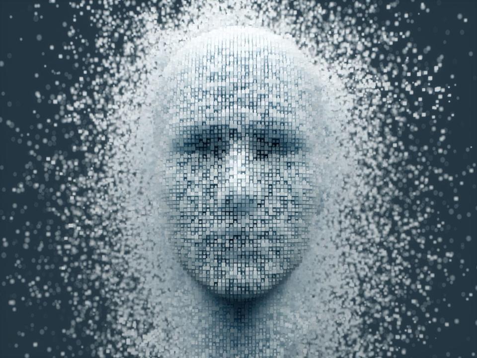 The outline of a human face emerging from a sea of individual pixels. 
