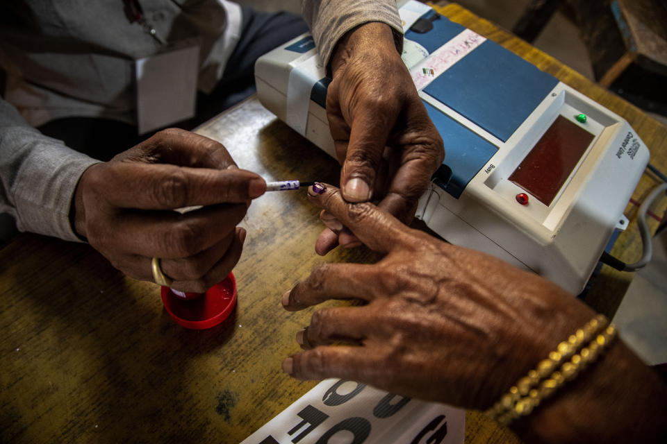 A polling officer applies indelible ink on a voter's finger at a polling station during the third phase of assembly election in Gauhati, India, Tuesday, April 6, 2021. (AP Photo/Anupam Nath)