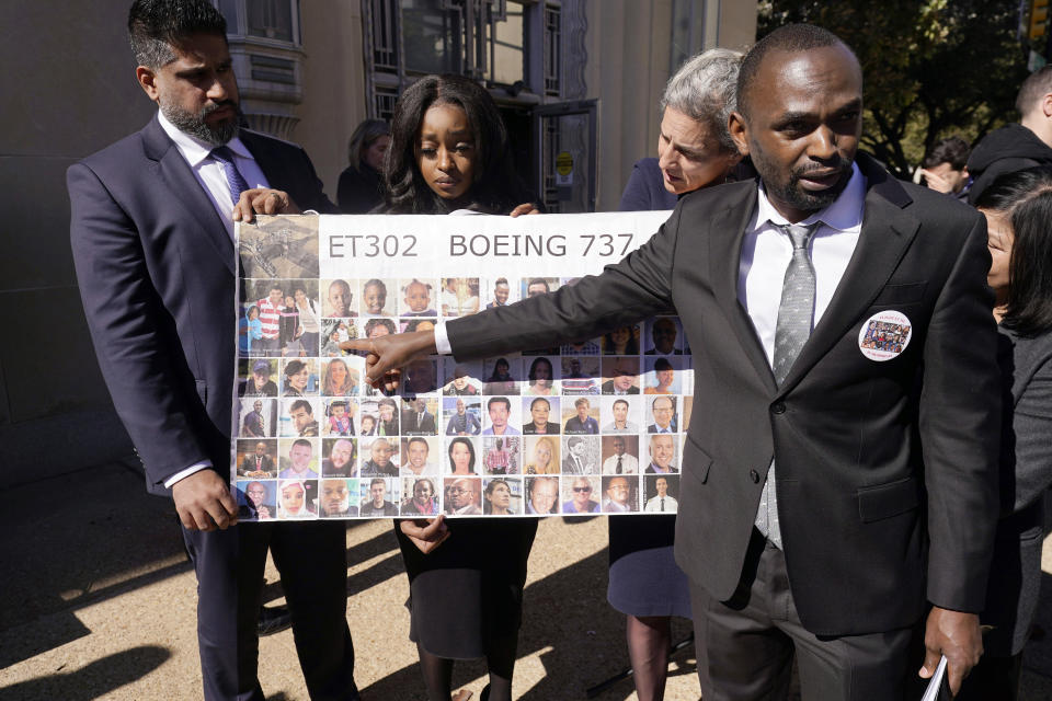 Paul Njoroge, right, points to photos of his wife and three children that were killed in the 2019 crash of Ethiopian Airlines 737 Max aircraft after a federal court hearing in Fort Worth, Texas, Thursday, Jan. 26, 2023. Holding the photos are, from left Naheed Noormohamed, Zipporah Kuria and Nadia Milleron, whom all also lost family on the same flight. (AP Photo/LM Otero)