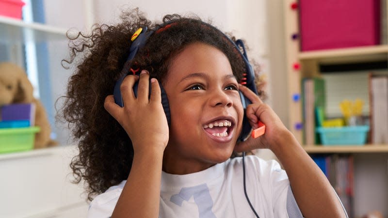 A younger student wearing the Logitech Zone Learn headphones in a school setting while talking into the pivoting boom microphone.