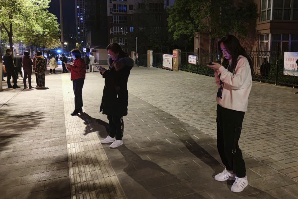 En esta fotografía facilitada por la agencia de noticias Xinhua, varias personas observan sus celulares en la calle el sábado 22 de mayo de 2021 después de que un sismo afectara Xining, en la provincia de Qinghai, en el centro de China. (Zhang Long/Xinhua vía AP)