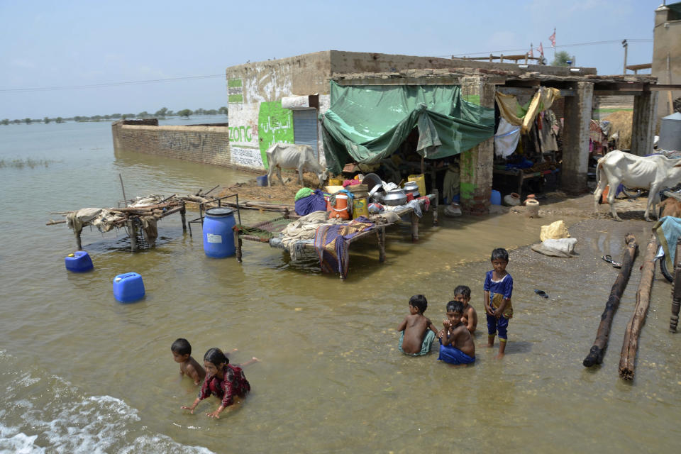 Children play in floodwaters next to their home, in Sohbatpur, a district of Pakistan's southwestern Baluchistan province, Monday, Aug. 29, 2022. International aid was reaching Pakistan on Monday, as the military and volunteers desperately tried to evacuate many thousands stranded by widespread flooding driven by "monster monsoons" that have claimed more than 1,000 lives this summer. (AP Photo/Zahid Hussain)