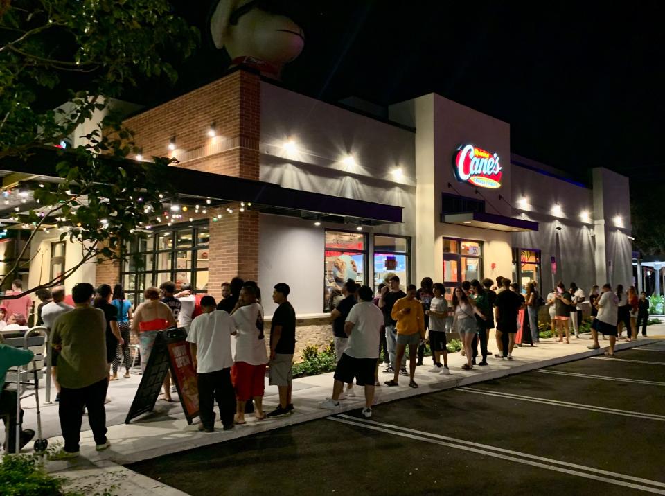 People wait outside of Raising Cane's grand opening Tuesday night in Boynton Beach. Most standing in line reported a wait of more than one hour.