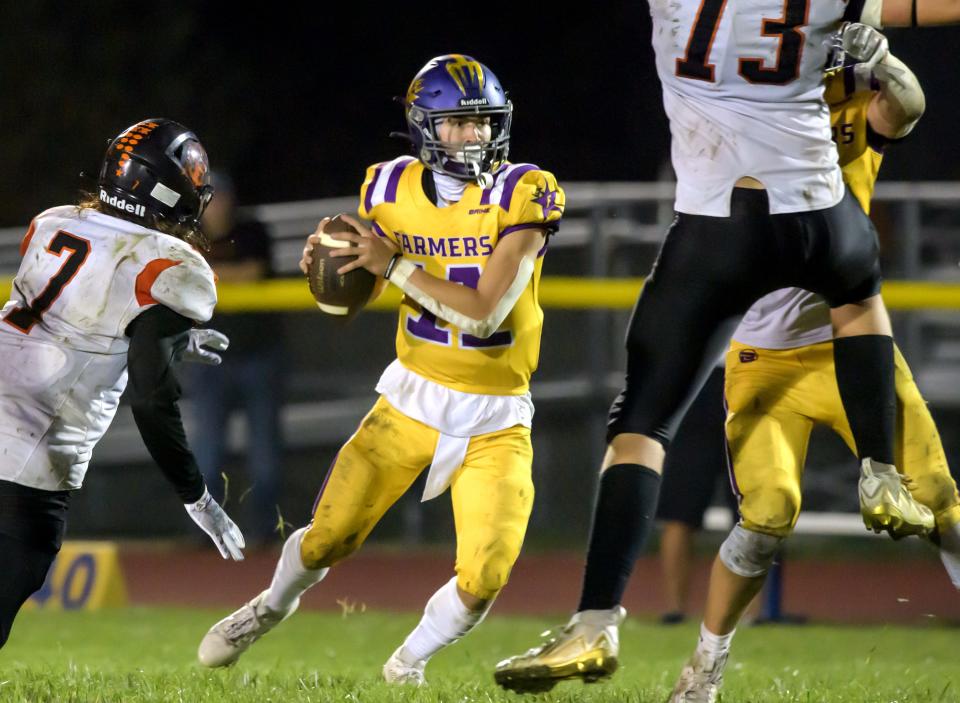 Farmington quarterback Lane Wheelwright (11) comes under pressure as he tries to pass the ball in the second half of their varsity football game Friday, Sept. 22, 2023 in Farmington. The Farmers defeated the Elmwood/Brimfield Trojans 30-26.