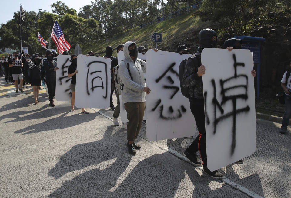 Protesters march with the words "Missing Classmate Chow" at the University of Science and Technology in Hong Kong on Friday, Nov. 8, 2019. Chow Tsz-Lok, a student from the University who fell off a parking garage after police fired tear gas during clashes with anti-government protesters died Friday, in a rare fatality after five months of unrest that intensified anger in the semi-autonomous Chinese territory. (AP Photo/Kin Cheung)