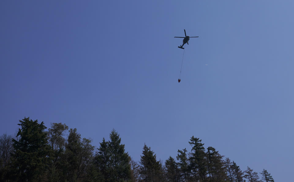 A helicopter flies after making a water drop Wednesday, Sept. 9, 2020, on a wildfire burning in Bonney Lake, Wash., south of Seattle. (AP Photo/Ted S. Warren, Pool)