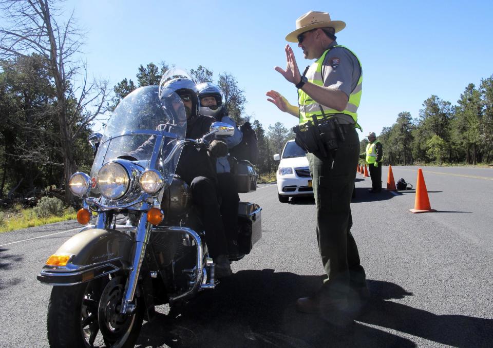 Grand Canyon National Park Ranger Jason Morris talks to people on a motorcycle at the closed park entrance on Thursday, Oct. 3, 2013 in Ariz. More than 400 national parks are closed as Congress remains deadlocked over federal government funding. (AP Photo/Brian Skoloff)