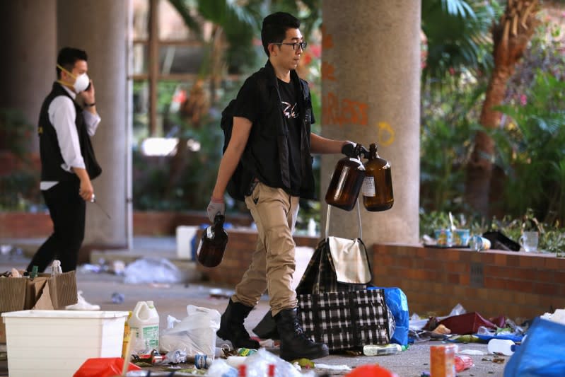 Police and firefighting personnel move Molotov cocktails, flammable materials and liquids into a corner, inside the Hong Kong Polytechnic University (PolyU) in Hong Kong, China