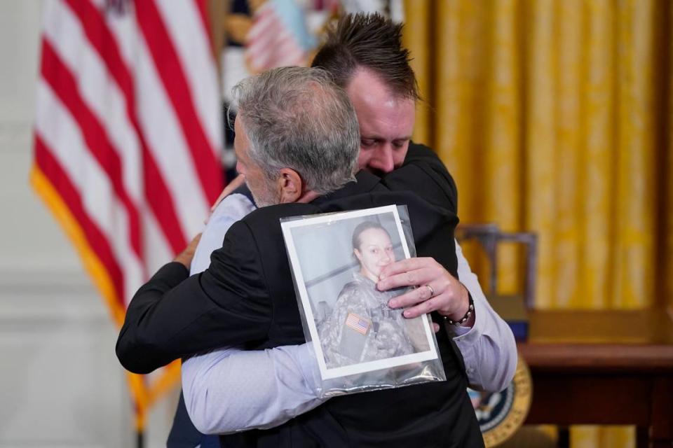 Activist and entertainer Jon Stewart hugs Sri Benson, husband of Katie Benson who served in Kuwait and died of mesothelioma, as they arrive to attend an event where President Joe Biden will sign the “PACT Act of 2022” in the East Room of the White House, Wednesday, Aug. 10, 2022, in Washington. (AP Photo/Evan Vucci)