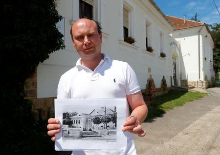 Charlie Mount, general manager of the Royal Tokaji Wine Company, holds up an old photo of the former home of the Zimmermann family which now houses the offices of the company in Mad, Hungary, July 18, 2016. Picture taken July 18, 2016. REUTERS/Laszlo Balogh