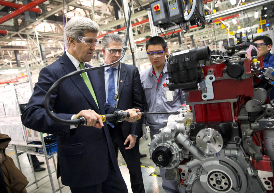 U.S. Secretary of State John Kerry, left, torques an engine bolt during a tour of the Foton Cummins Engine plant in Beijing, China Saturday, Feb. 15, 2014. Kerry toured the plant and made remarks on climate change cooperation between the United States and China. (AP Photo/Evan Vucci, Pool)