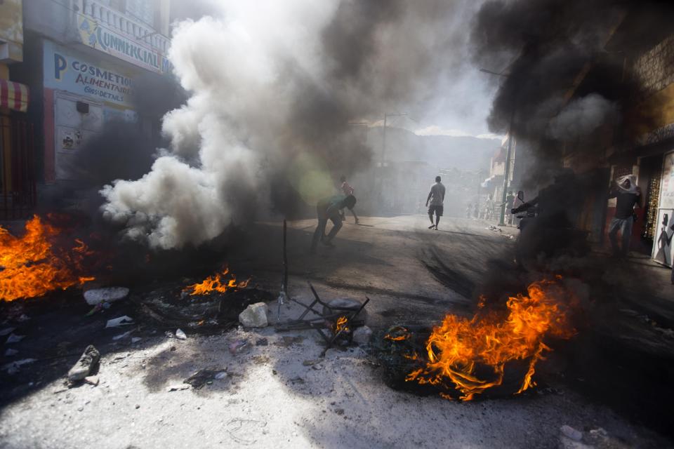 Demonstrators block a road with a burning barricade during a strike that is part of protests demanding to know how Petro Caribe funds have been used by the current and past administrations, in Port-au-Prince, Haiti, Monday, Nov. 19, 2018. Much of the financial support to help Haiti rebuild after the 2010 earthquake comes from Venezuela's Petro Caribe fund, a 2005 pact that gives suppliers below-market financing for oil and is under the control of the central government. (AP Photo/Dieu Nalio Chery)