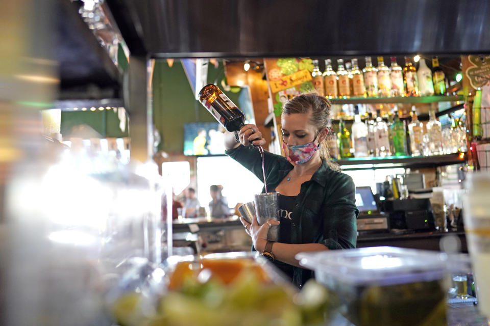 Bartender Alyssa Dooley makes a cocktail at Mo's Irish Pub, Tuesday, March 2, 2021, in Houston. Texas Gov. Greg Abbott announced Tuesday that he is lifting business capacity limits and the state's mask mandate starting next week. (AP Photo/David J. Phillip)