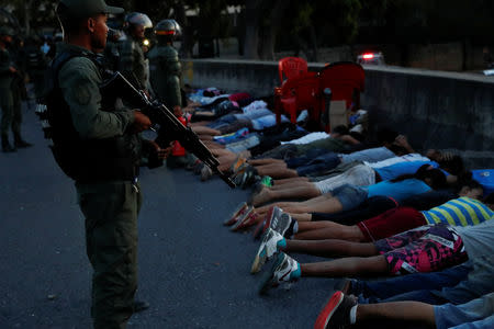 A security force member stands next to detainees on a street after looting during an ongoing blackout in Caracas, Venezuela March 10, 2019. REUTERS/Carlos Garcia Rawlins