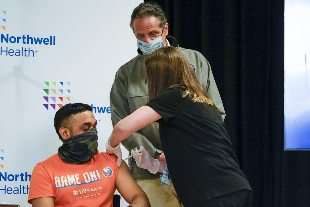 Gov. Andrew Cuomo, center, watches as Local 28 Sheet Metal Worker Ashwinkoemar Soechit inoculated with the first dose of the Pfizer vaccine during a news conference, Wednesday, April 14, at a pop up COVID-19 vaccination sight at Belmont Park in Elmont, N.Y. 