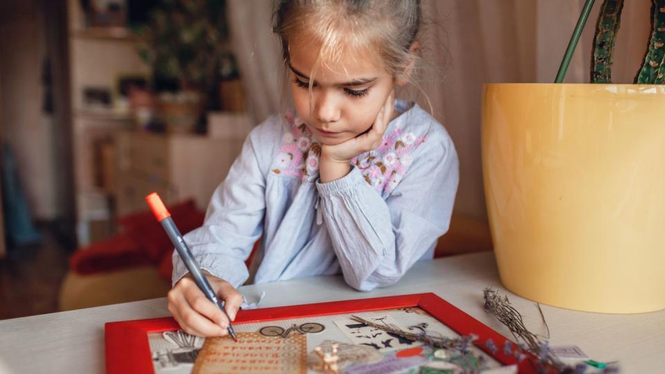 cute girl dreaming about travel to france and creating mood board with sheets of paper, pictures and words